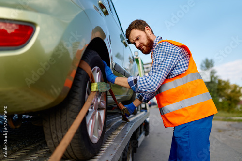 Fotografie Tow truck operator fixing car on platform