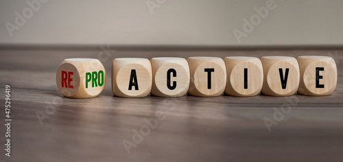 Cubes, dice or blocks with reactive and proactive on a wooden background