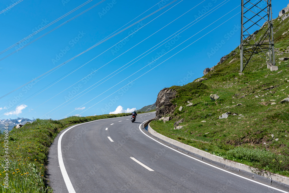 Fototapeta premium Power lines cross the Nufenenpass road near Ulrichen