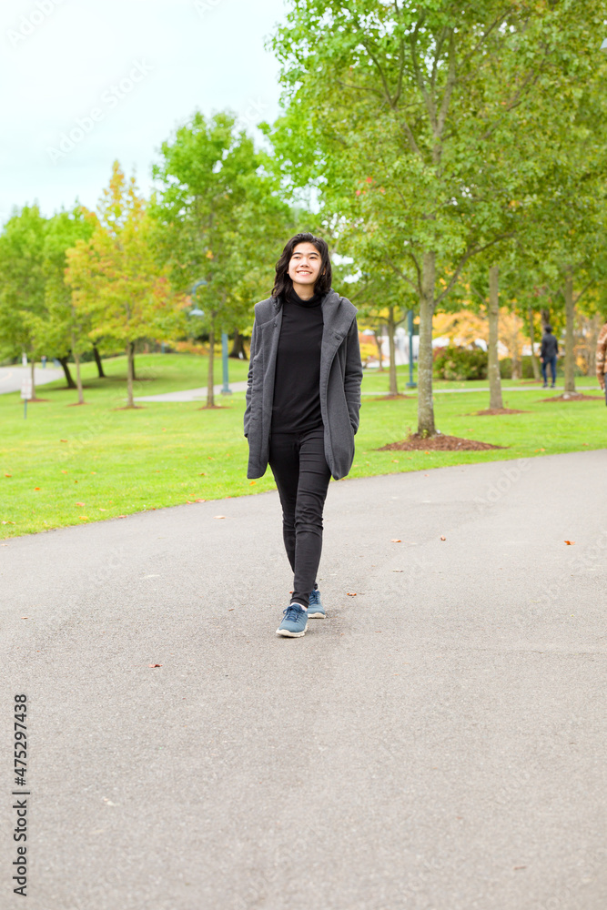 Fototapeta premium Biracial Asian teen girl enjoying fall autumn leaves along road