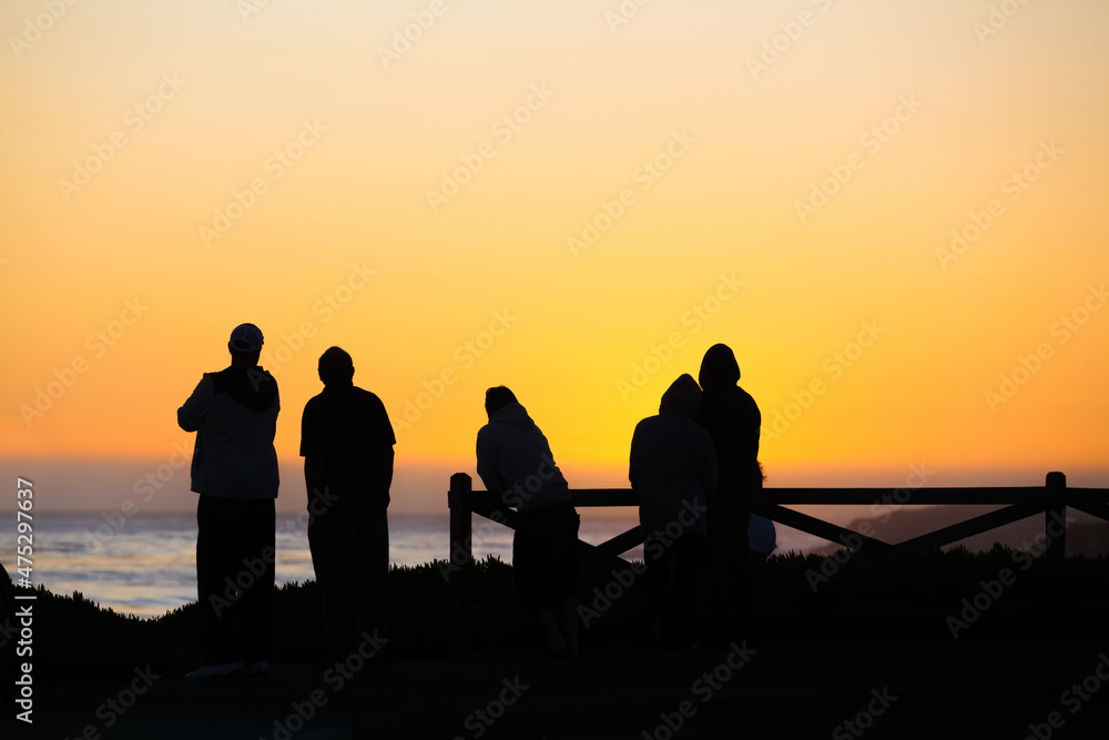 Silhouette of people enjoying beautiful sunset off California coast