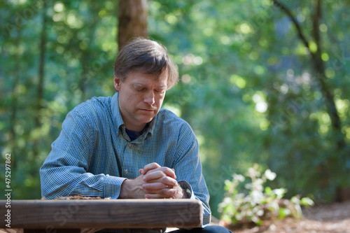 Man praying alone in middle of forest