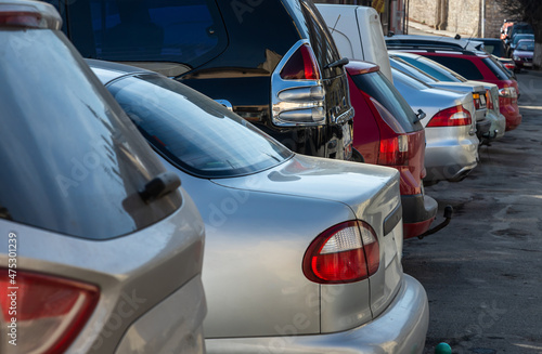 Closeup of rear, back side of golden car with other cars parking in outdoor parking area.