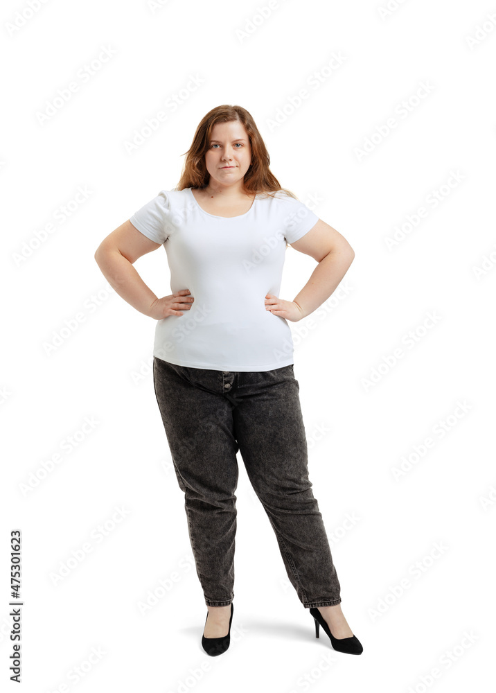 Full-length portrait of plus-size woman wearing white t-shirt and jeans posing isolated on white studio background. Body positive concept Full-length portrait of plus-size woman wearing white t-shirt and jeans posing isolated on white studio background. Body positive concept