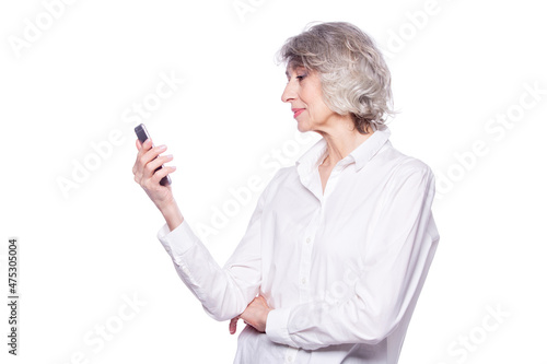 Beautiful mature grey-haired woman is smiling using a smartphone watching video or chatting isolated on white background