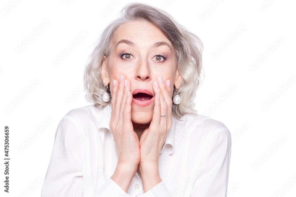Portrait of a modern mature woman looking at camera with open mouth and hands at her face scared, surprised and shocked isolated on white background Portrait of a modern mature woman looking at camera with open mouth and hands at her face scared, surprised and shocked isolated on white background
