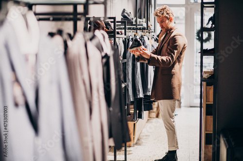 Young handsome man choosing cloth at shop