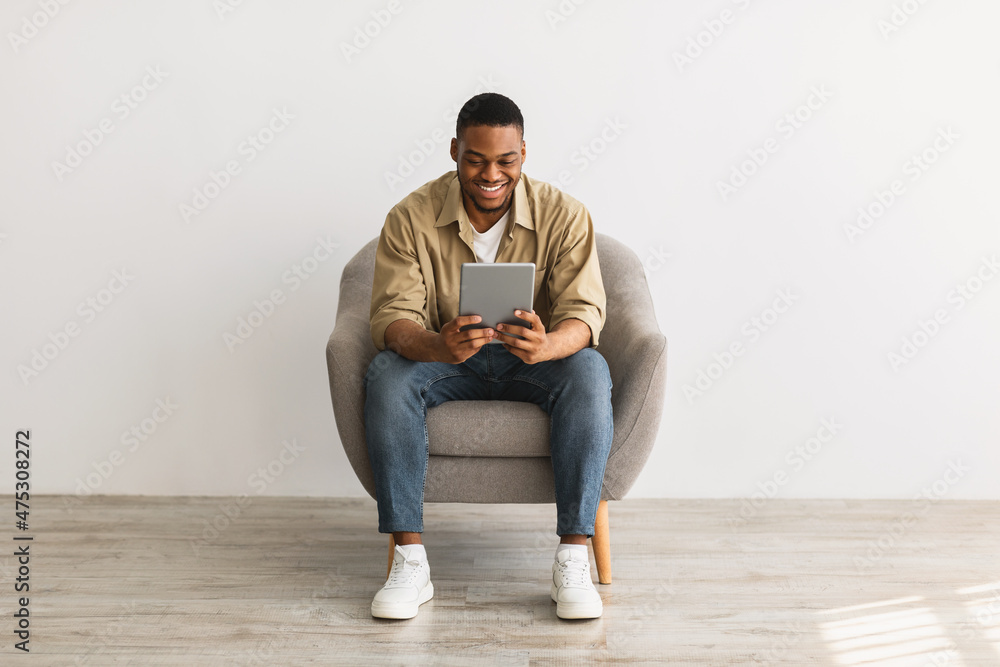Happy African Man Using Digital Tablet Sitting Over Gray Background