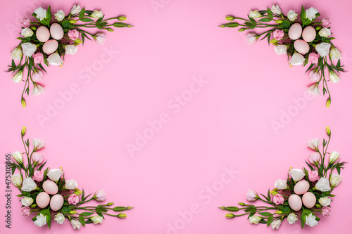 Easter background with Easter eggs and spring flowers. Top view with copy space. Nest with eggs decorated with beautiful flowers on a pink background.