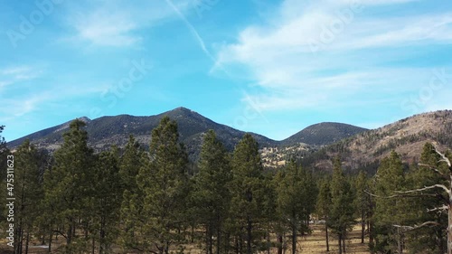 An aerial shot of the San Francisco Peaks, located north of Flagstaff, Arizona. From left to right, Agassiz, Fremont and Doyle Peaks are seen. The camera makes a pedestal up motion from behind trees. photo