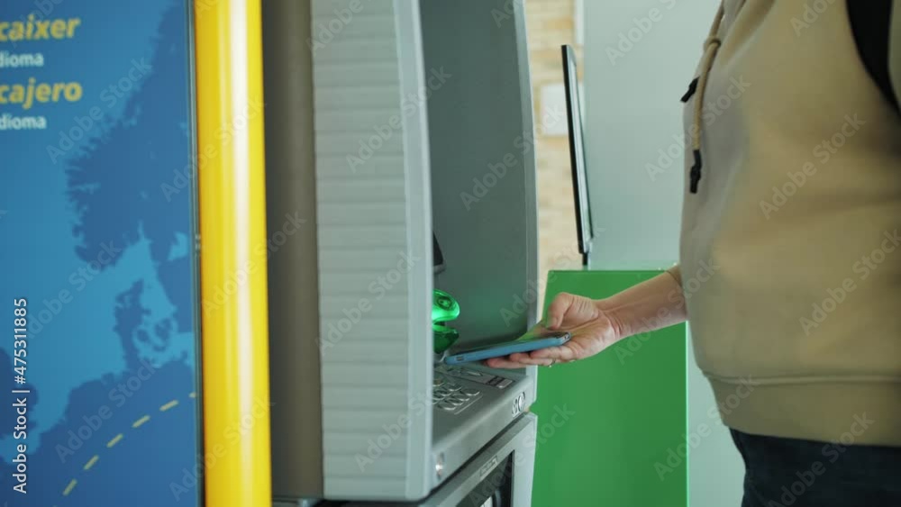 Close up of withdrawing money from atm with a mobile phone a NFC, terminal airport. Close up of withdrawing money from atm with a mobile phone a NFC, terminal airport.