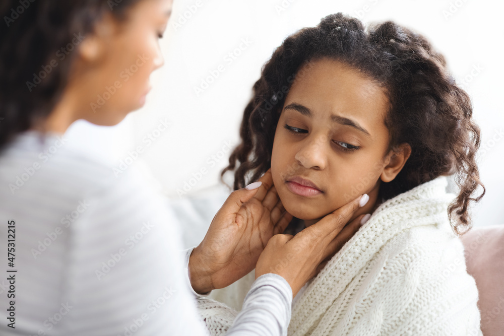 African american mother rubbing her sick daughter neck African american mother rubbing her sick daughter neck
