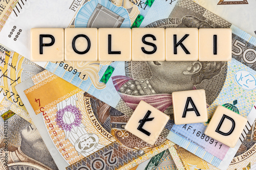 The sentence "Polski Ład" translated as "Polish Order" and many Polish banknotes. New taxation rules in Poland. Photo taken under artificial, soft light