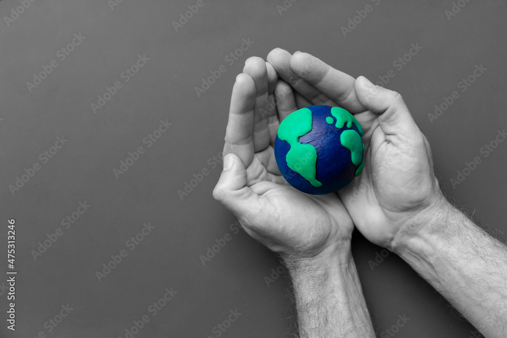 Black and white man's hands holding the Earth in color