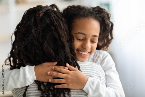 Adorable black school girl hugging her mom