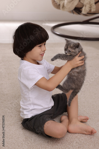 Cute little boy with kitten on floor at home. Childhood pet