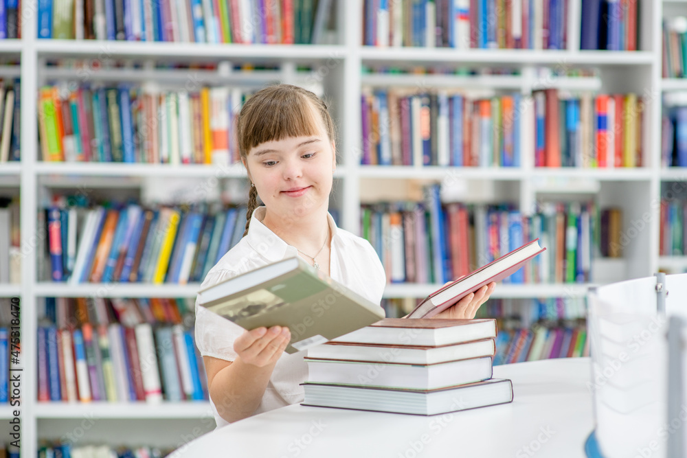 Smiling young girl with Downs syndrom holds books at library Smiling young girl with Downs syndrom holds books at library