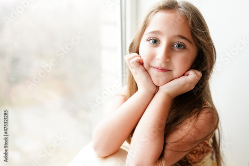 happy little girl a on white background sitting on the window sill
