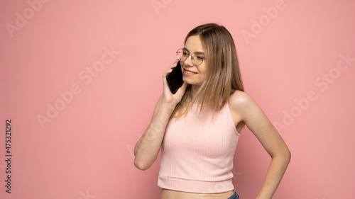 Young blonde woman over isolated pink background sending a message with the mobile.