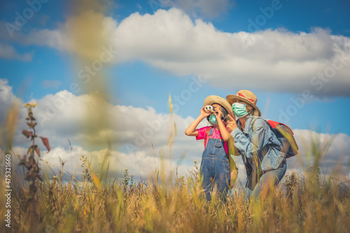 Children and mother learning and playing on grassland on blue sky and white clouds background, happy time for people of family