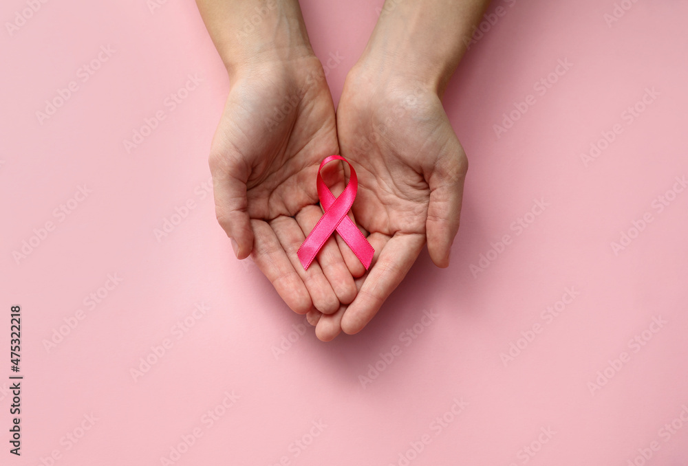 Woman holding pink ribbon on color background, top view with space for text. Breast cancer awareness concept Woman holding pink ribbon on color background, top view with space for text. Breast cancer awareness concept