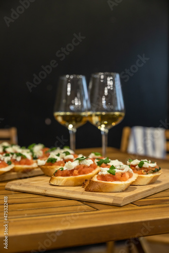 Toast or bruschetta with tomatoes, mozzarella and basil and two glasses with white wine. An appetizer for a banquet or buffet.