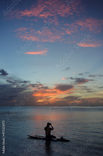 夕焼けの静かな海で写真を撮る人