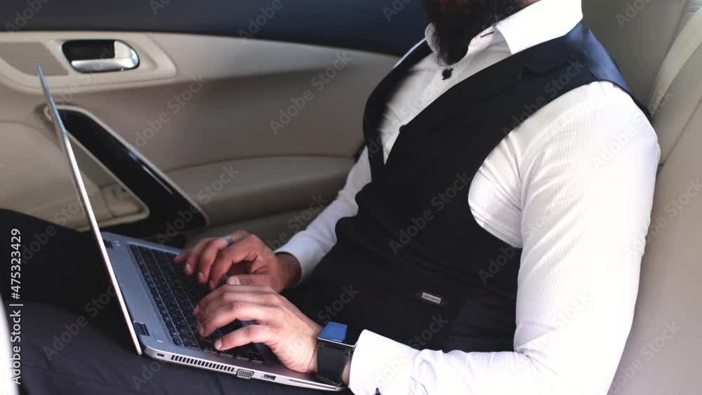 Indian businessman working with laptop in backseat of car Indian businessman working with laptop in backseat of car