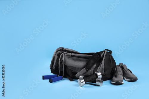 Grey bag and sports accessories on light blue background  space for text