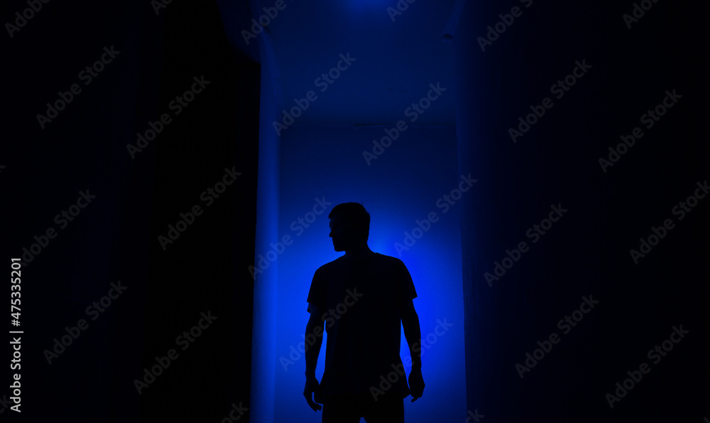 Silhouette of a guy in the dark.
Man in blue light.
