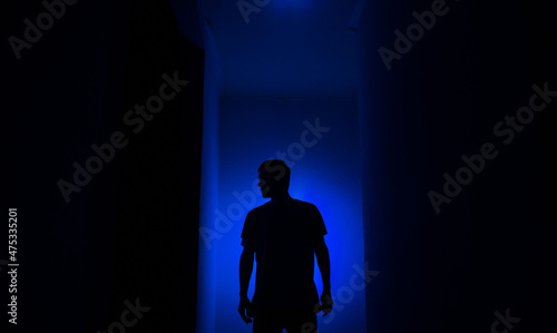 Silhouette of a guy in the dark.
Man in blue light.