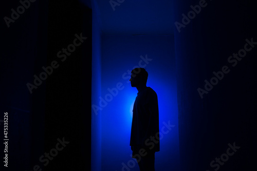 Silhouette of a guy in the dark.
Man in blue light.