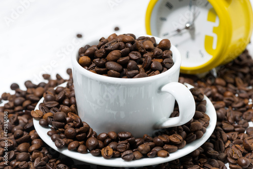 cup with coffee beans and an alarm clock  conceptual photography  closeup