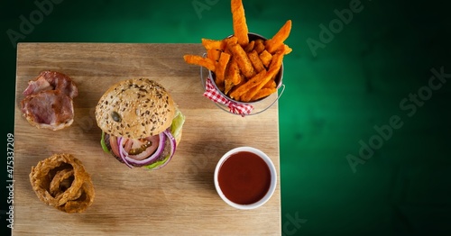 Overhead view of fast food on a wooden tray against green background