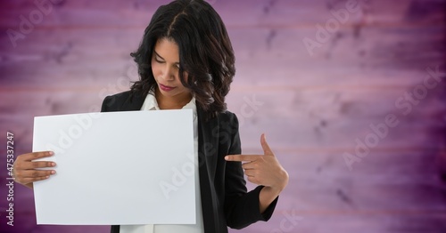 Composite image of caucasian woman pointing towards a blank placard on purple textured background