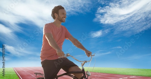 Composite image of caucasian man riding a bicycle against sports track and blue sky