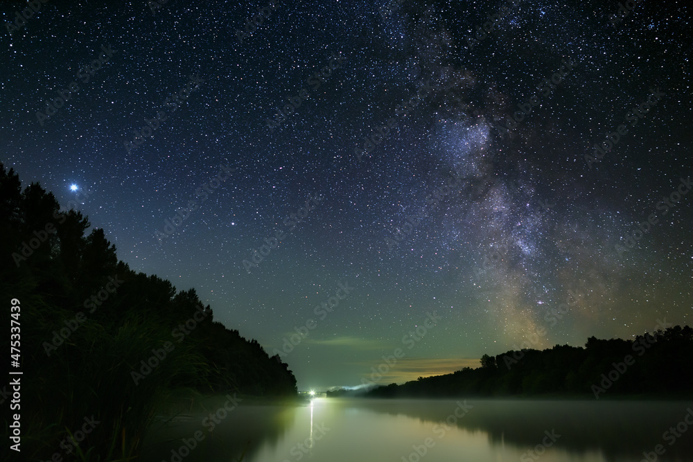 Fototapeta premium Bright stars of the Milky Way in the night sky over the river with fog. Wonderful place for landscape.