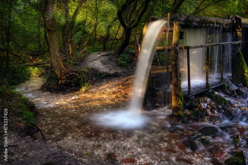 Fast flow of pure spring water on an old mill. Autumn landscape with a waterfall.