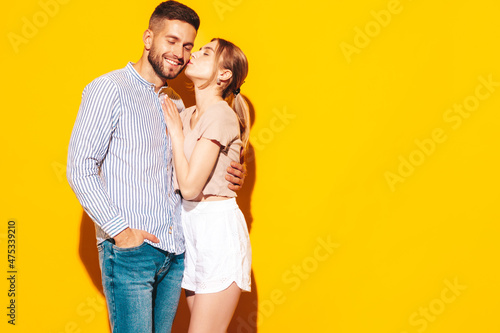 Sexy smiling beautiful woman and her handsome boyfriend. Happy cheerful family having tender moments near yellow wall in studio.Pure cheerful models hugging.Embracing each other.Kissing in cheek