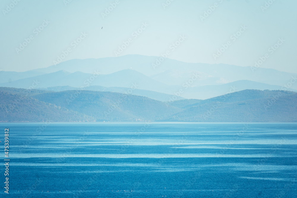 Obraz premium Natural blue background. Seascape with mountains on the horizon.