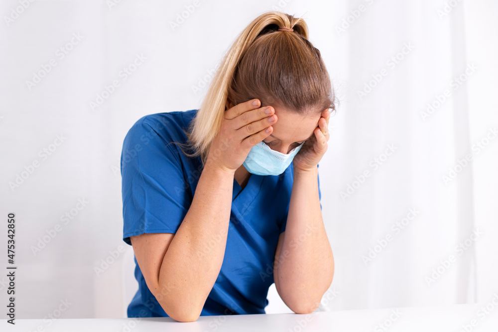 Tired and exhausted nurse or doctor. Stressed female medical worker with protective face mask, depressed after working over hours due to coronavirus outbreak. Covid 19. Medicine, healthcare, pandemic