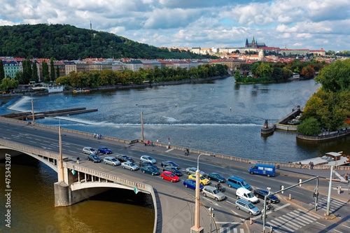 Scenery of Jirasek ( Jiraskuv ) Bridge over Vltava River in Prague, capital city of Czech Republic, with the majestic Castle & St. Vitus Church in distant background and colorful houses by riverside photo