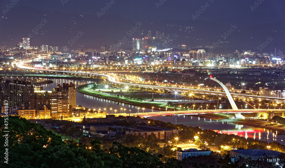 Aerial panorama of Taipei Downtown at night with Dazhi Bridge over Keelung River, parks and highways along the riverside and skyscrapers in Nangang area at dusk ~ A romantic night scape of Taipei City