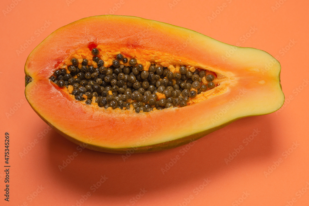 Papaya fruit on a orange background. Half papaya. Papaya fruit on a orange background. Half papaya.