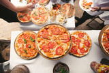 There are many different freshly prepared pizzas on the buffet table.