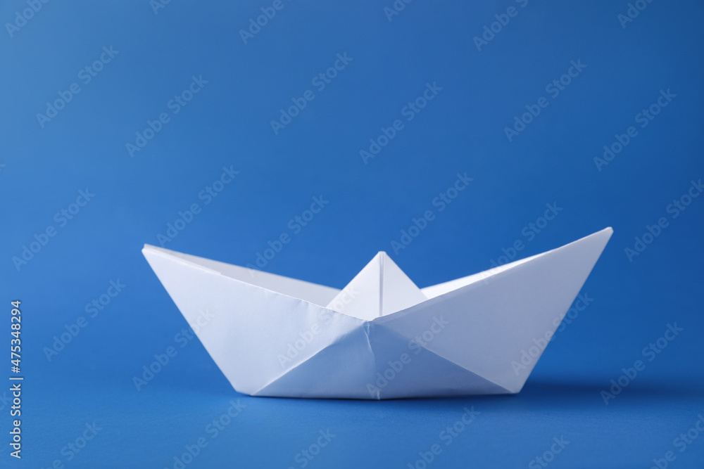 Handmade white paper boat on blue background. Origami art Handmade white paper boat on blue background. Origami art