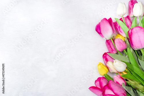 Valentine's Day concept Mother's Day, Birthday background. Spring tulip flowers with heart, gift and blank notepad for writing on white fluffy fur background, flatlay