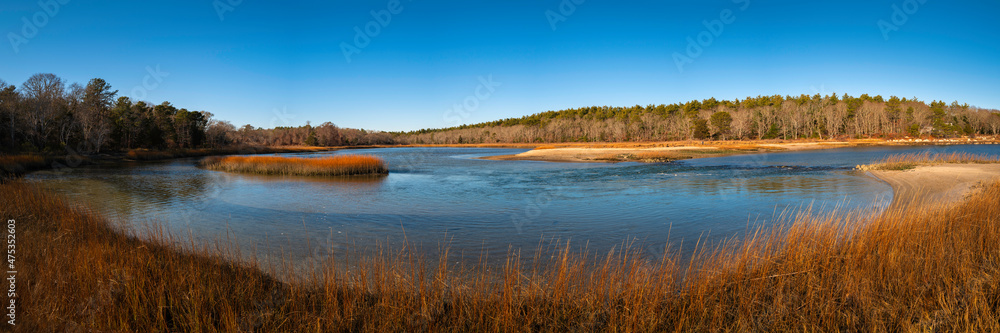 Panoramic seascape with curving beach, wildplants, beach grasses, forest, and clear blue sky in Buzzard Bay. Tranquil seascape over the Widows Cove and beach in Wareham, Massachusetts in winter.