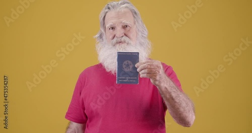 Elderly man holding Brazilian workbook smiling at camera. Inss concept.