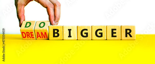 Dream and do bigger symbol. Businessman turns wooden cubes and changes words dream bigger to do bigger. Business and dream and do bigger concept. Beautiful white background, copy space. photo